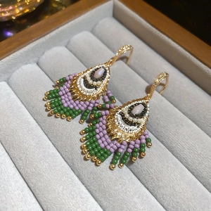 Detail of green and purple beaded fringe earrings with opal stone in a jewelry box