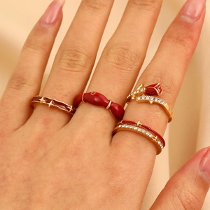 Close-up of four-piece gold ring set featuring red enamel rose and crystal accents