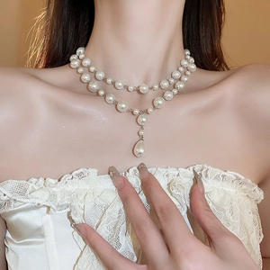 Detail of elegant double-layered necklace featuring white pearls and a teardrop pendant