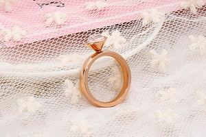Dettaglio anello oro rosa con grande cristallo sfaccettato su pizzo rosa
