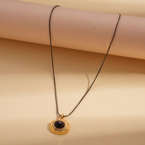 Macro shot of 18k gold plated necklace with dark tiger eye stone pendant on beige base