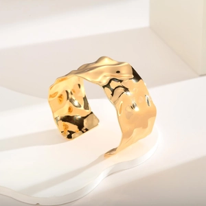 Minimalist wide open cuff bracelet with hammered 18K gold finish on a white stand
