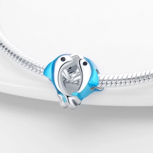 Close-up of silver-plated kissing dolphin charm with blue enamel on a bracelet