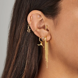 Detailed close-up of a golden ear jewelry set with lightning bolt and snake pendants