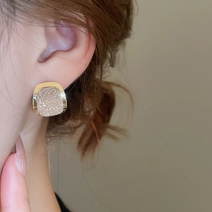 Close-up of 18k gold plated square stud earring with sparkling champagne finish on model