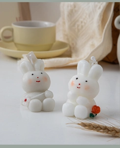 Close-up of cute white and grey rabbit scented candles with floral details on a cozy table