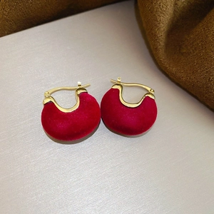 Vue détaillée de boucles d'oreilles en velours rouge avec clous dorés sur fond gris