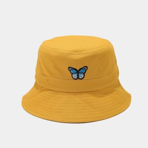 Close-up detail of blue butterfly embroidery on the yellow cotton bucket hat