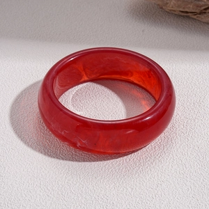 Close-up of translucent red resin bangle with natural swirling inner textures