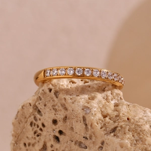 Detail of 18K gold plated stainless steel zircon eternity ring on a natural rock texture