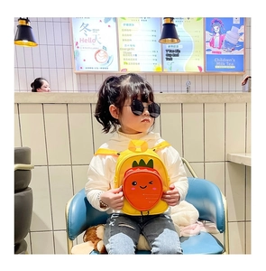 Toddler modeling a cute carrot-shaped mini canvas backpack with a winking face detail