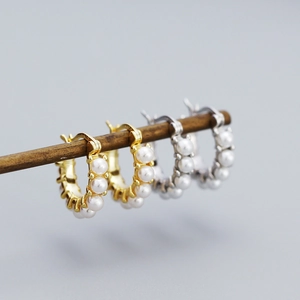 Detailed shot of gold and silver hoop earrings with small white pearl inlays