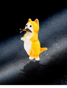 Macro detail of cute orange and white cat brooch holding a small golden fish