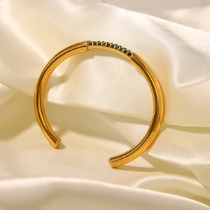 Dettaglio del bracciale aperto in acciaio dorato con pietre preziose verdi incastonate