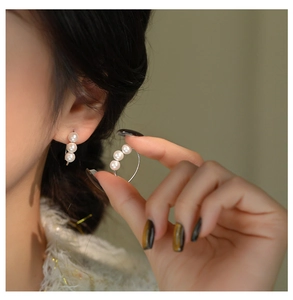 Detailed view of three white pearls vertically arranged on a s925 silver hook earring