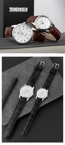 Classic quartz couple watches with leather straps and date display on a desk