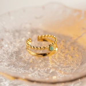 Detail of vintage French style gold ring with light green stone on textured tray