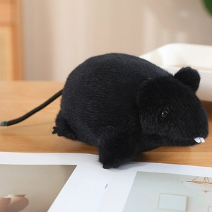 Detalle del suave peluche de ratón negro con dientes blancos sobre una mesa de madera