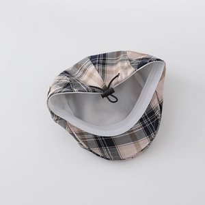 Detail view of plaid kids flat cap with white lining and adjustable drawstrings