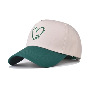Detail of two-tone baseball cap with green brim and printed heart paw logo on white canvas