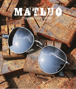 Close-up of retro metal round sunglasses frame and E3447 temple detail on rust background