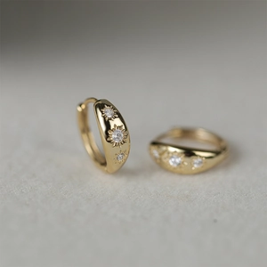 Detailed view of gold starburst hoop earrings with sparkling cubic zirconia inlay