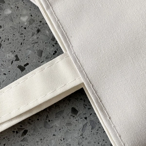 Close-up of sturdy reinforced stitching on white canvas tote bag handle joints