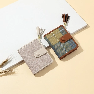 Detail of short wallets in beige and yellow plaid with gold tassel and magnetic closure