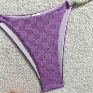 Macro shot of purple checkered bikini bottom with pearl straps and silver triangle buckle