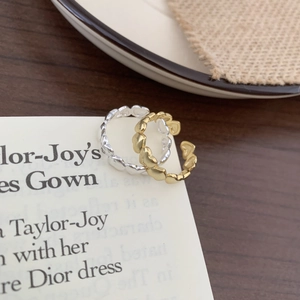 Detail of minimalist gold and silver heart-shaped open rings on a lifestyle background
