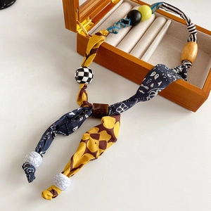 Detail of printed fabric wraps and decorative beads on a vintage bohemian heart necklace