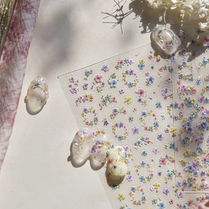 Pastel floral nail stickers on cream nail tips with soft nature lighting effect