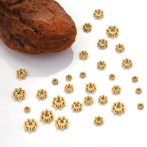 Golden flower snowflake spacers in various sizes for DIY jewelry making on white background