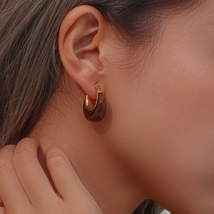 Close-up of elegant gold plated acrylic hoop earring worn by a female model