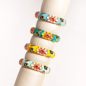 Macro view of four colorful enamel flower rings with gold plating and vintage oil drop detail