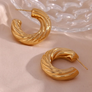 Detailed close-up of 18K gold-plated hollow twisted C-shape hoop earrings on silk