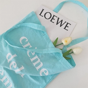 Detail einer hellblauen Segeltuchtasche mit Creme de la Schriftzug und Tulpen Deko