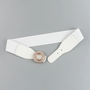 Detailed view of women's white elastic belt with glittering rhinestone-set gold circular buckle