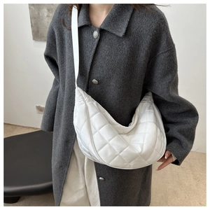 Close-up of white quilted crescent bag showing the puffy diamond stitch texture and strap