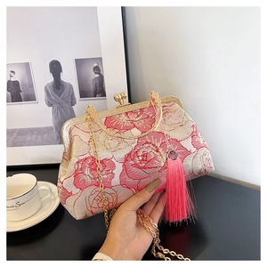 Detail view of floral embroidery handbag with golden frame and silk tassel accent