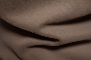 Macro shot of dark brown knit fabric showing soft texture and premium cotton material