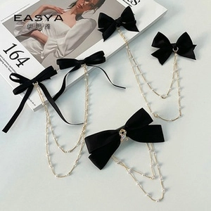 Detailed view of black velvet bow pins with layered pearl fringe and gold chains