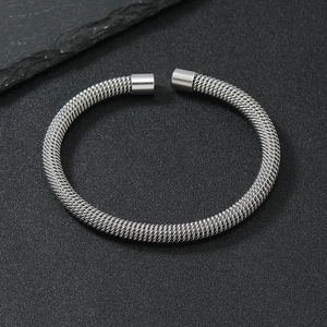 Detailed close-up of a silver mesh stainless steel cuff bracelet on a dark background