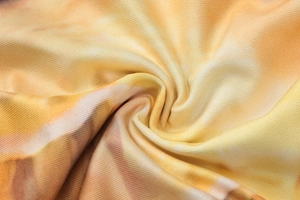 Close-up of orange ribbed knit fabric with marble tie-dye pattern and spiral texture