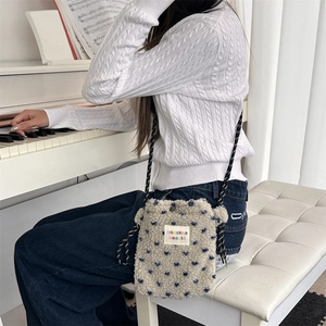 Detail of plush cream lamb wool phone bag with blue dots and black cord strap