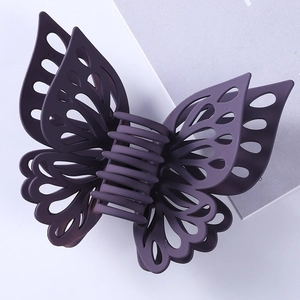 Close-up of matte dark purple butterfly hair claw with intricate hollow wing details