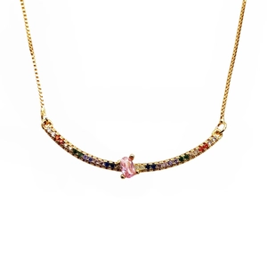 Macro detail of gold necklace featuring multi-colored gemstones and pink center stone
