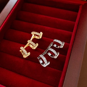 Macro detail of H-shaped 18k gold plated ear clips with sparkling zircon inlay