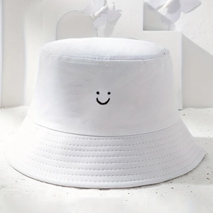 Détail du bob en toile blanche avec motif de visage souriant brodé en noir