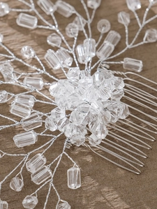 Close-up of handmade bridal hair comb with silver wire and crystal beads on wood
